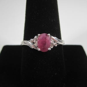 May include: A white ceramic mug with a black handle and the text "But First, Coffee" in a handwritten style. The mug is on a white surface. The mug is approximately 10 cm tall.