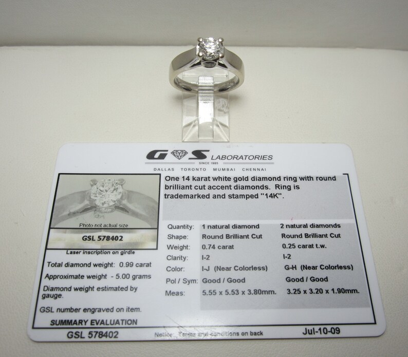 May include: A GSL Laboratories diamond ring certificate with a photo of a white gold diamond ring with round brilliant cut diamonds. The certificate states the ring is 14 karat white gold with a total diamond weight of 0.99 carats. The certificate number is GSL 578402 and the date is Jul-10-09.