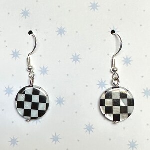 May include: A pair of silver dangle earrings with round black and white checkered shell cabochons.