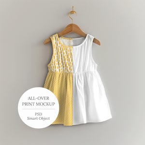 Könnte beinhalten: Ein ärmelloses gelbes und weißes Kleid mit einem geometrischen Muster auf der Vorderseite und einem einfarbigen weißen Rücken. Das Kleid hängt an einem Holzbügel vor einem grauen Hintergrund.