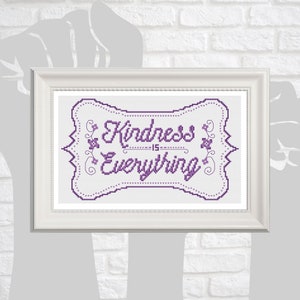 Puede incluir: Un diseño de punto de cruz enmarcado con un esquema de color morado y blanco. El diseño presenta un marco decorativo con acentos florales y el texto "Kindness is Everything".