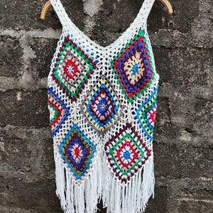 May include: White crochet tank top with colorful granny square pattern and fringe trim.