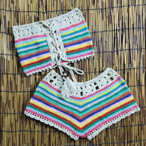 May include: A crochet bikini top and bottom set with a rainbow stripe pattern. The top has a lace-up front and the bottom has a scalloped edge.