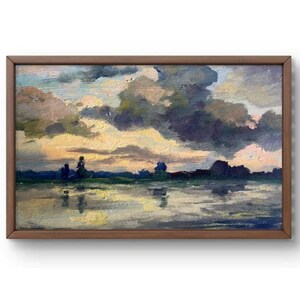 Puede incluir: Una pintura al óleo enmarcada que representa una escena de paisaje con un lago en primer plano y un cielo nublado en el fondo. El lago está tranquilo y refleja el cielo. Las nubes son una mezcla de gris y blanco, con un toque de rosa en la distancia.