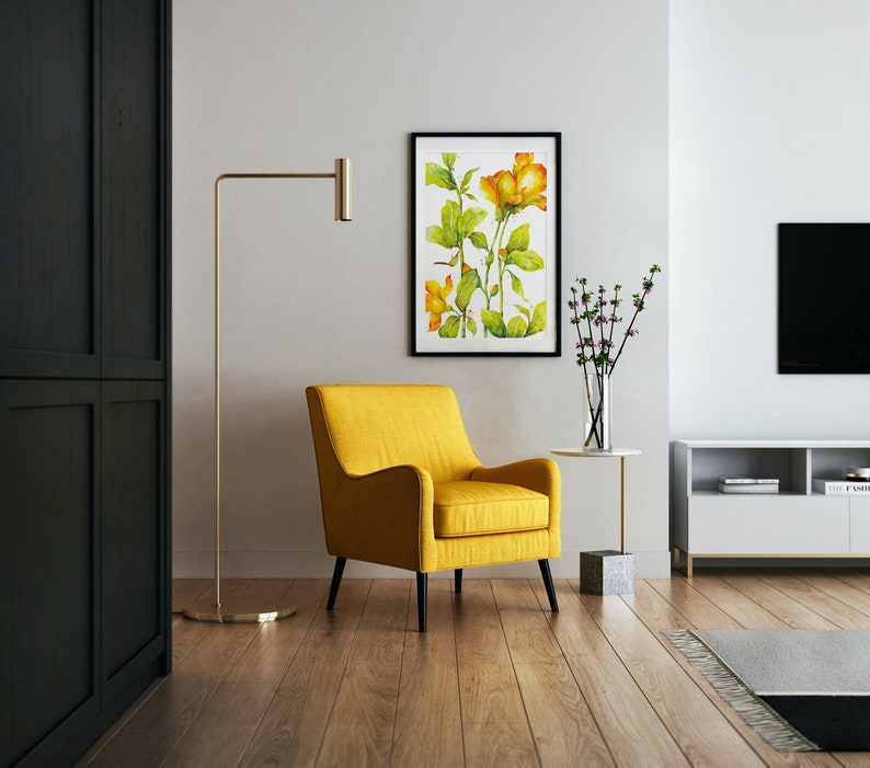 May include: A yellow armchair with black legs sits in a living room with a framed watercolor painting of yellow flowers, a floor lamp, and a white entertainment center with a television.