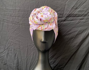 May include: A purple and white patterned satin head wrap tied in a rose shape.