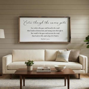 May include: A rectangular wall sign with a dark wood frame and a white background featuring black text that reads: Enter through the narrow gate. For wide is the gate and broad is the road that leads to destruction, and many enter through it.
