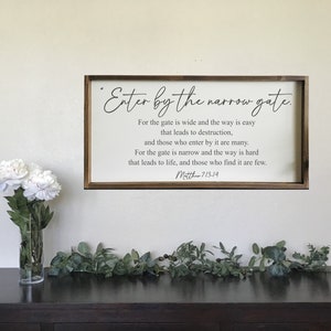 Puede incluir: Un letrero de madera enmarcado con fondo blanco y texto negro. El texto dice "Entrad por la puerta estrecha. Porque ancha es la puerta y espacioso el camino que lleva a la perdición, y muchos son los que entran por ella. Porque estrecha es la puerta y angosto el camino que lleva a la vida, y pocos son los que la hallan. Mateo 7:13-14"