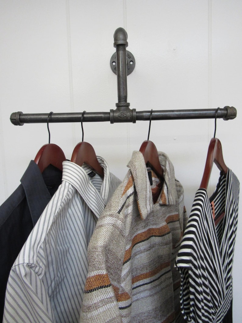 May include: A black metal pipe clothing rack with four hangers holding striped and patterned shirts.