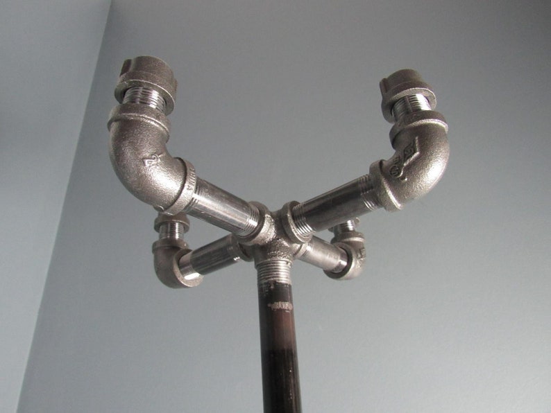 May include: A black metal coat rack with four hooks made from pipe fittings. The rack is mounted on a black metal pole.