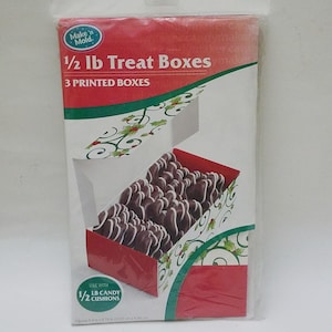 May include: A package of Make'n Mold 1/2 lb Treat Boxes. The boxes are white with red and green accents, and feature a holly and swirl design. The package includes 3 printed boxes, each measuring 5.5 in x 2.75 in x 6.09 in.