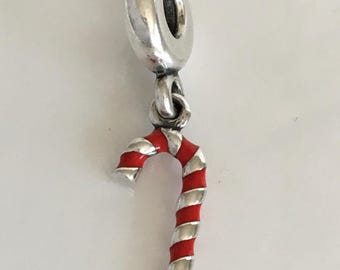 May include: A silver charm with a red and white candy cane design. The charm has a loop at the top with the markings "5925 ALE". The candy cane is red with white stripes.