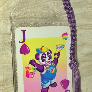 May include: A Jack of Spades playing card with a cartoon panda illustration, held in a clear plastic sleeve. The card has a purple braided bookmark attached. The panda is holding a paint bucket and brush.