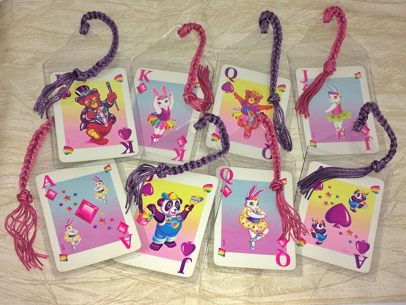 May include: A selection of playing card bookmarks, each with a cartoon animal illustration. The cards feature a bear, bunny, and panda. The bookmarks have braided tassels in pink and purple. The cards are in clear plastic sleeves.