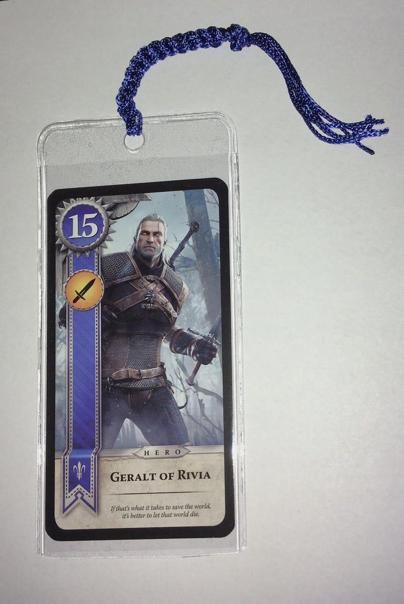 Peut inclure: Marque-page en plastique transparent avec une carte repr&eacute;sentant Geralt de Riv, personnage de la s&eacute;rie The Witcher. La carte a un design bleu et or avec le chiffre 15. Une corde tress&eacute;e bleue est attach&eacute;e en haut.