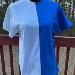 May include: A white and royal blue t-shirt with a vertical seam down the center.