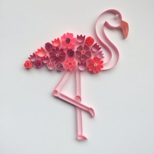 May include: A pink paper flamingo with a body of pink and red paper flowers. The flamingo is made of paper strips and is set against a white background. The flowers are various shades of pink and red.