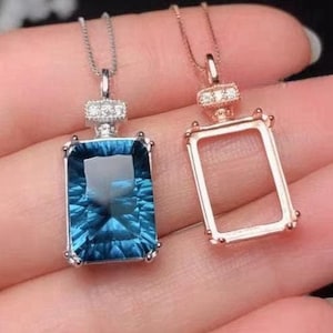 May include: Two silver necklaces with pendants. One pendant is a bezel setting with a large blue gemstone. The other pendant is a bezel setting with a clear space for a gemstone.