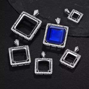 Peut inclure: Six montures de pendentif argentées avec des pierres de zircone cubique claires autour des bords. Une monture de pendentif a une pierre précieuse bleue au centre.