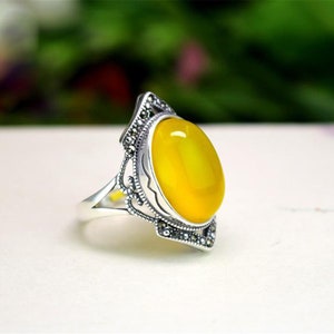 May include: A silver ring with a yellow oval gemstone set in a filigree design.