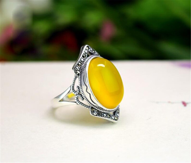 May include: A silver ring with a yellow oval gemstone set in a filigree design.