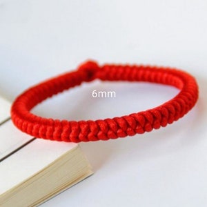 May include: A red braided bracelet with a 6mm width. The bracelet is made of a thick, woven cord.