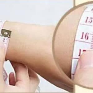May include: A white measuring tape with red markings is wrapped around a person's wrist. The tape reads 15, 16, and 17 inches.