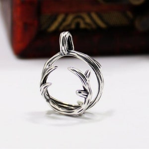 May include: Silver pendant featuring a circular design with a detailed antler branch motif.