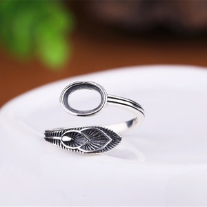 May include: Silver ring with an oval-shaped bezel and a leaf design. The ring is adjustable and can be worn on any finger.