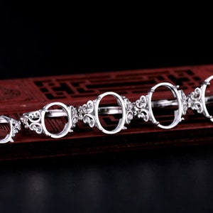 May include: Six silver rings with oval-shaped settings. The rings are arranged in a row from smallest to largest. The rings have a delicate, ornate design.