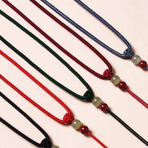 Puede incluir: Cinco cordones de diferentes colores con una cuenta verde y roja al final. Cuerda gruesa: 2 mm.