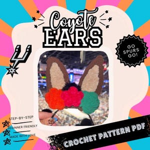 May include: A crochet headband featuring brown and tan coyote ears with orange, red, and green flower accents. The text "Coyote EARS" is displayed above the ears. Additional text includes "GO SPURS GO!", "STEP-BY-STEP", "BEGINNER FRIENDLY", "MADE WITH LOVE", and "CROCHET PATTERN PDF".