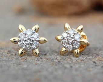 May include: A pair of gold stud earrings with a starburst design set with small diamonds.