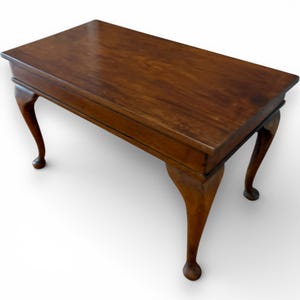 May include: A dark brown wooden table with a rectangular top and curved legs. The table's legs are a lighter shade of brown and end in a rounded foot. The table is approximately 76 cm long. A classic furniture piece.
