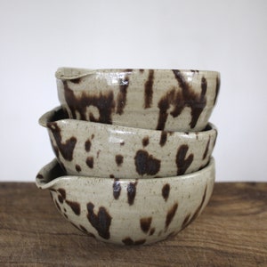 Handmade speckled Nordic Pottery bowls stacked together to show glaze variation and form.