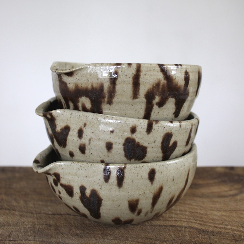 Handmade speckled Nordic Pottery bowls stacked together to show glaze variation and form.