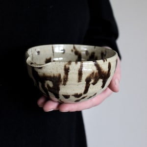 Handmade ceramic matcha bowl with speckled glaze, shown in hand to display size and shape.