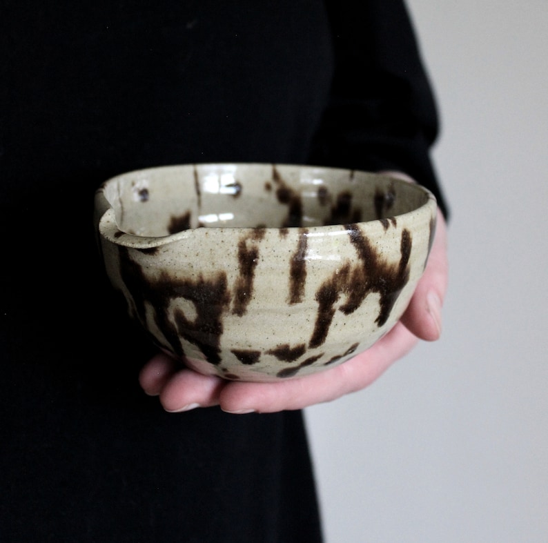 Handmade ceramic matcha bowl with speckled glaze, shown in hand to display size and shape.