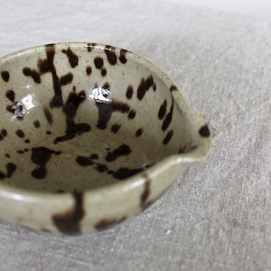 Close-up of speckled ceramic glaze on handmade matcha bowl with a spout.