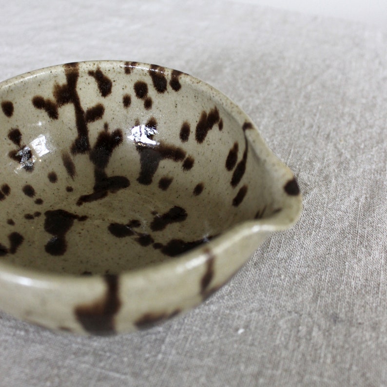 Close-up of speckled ceramic glaze on handmade matcha bowl with a spout.