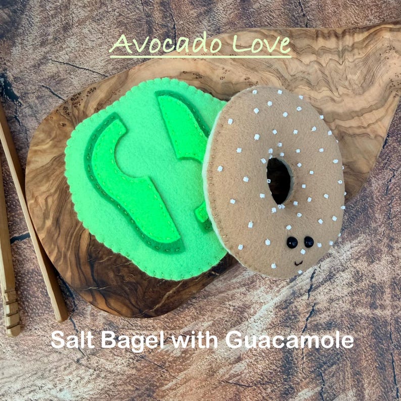 May include: A felt craft set featuring a light green avocado slice and a tan bagel with white seed accents and two black bead eyes. The text Avocado Love and Salt Bagel with Guacamole is visible. The items are made of felt fabric.