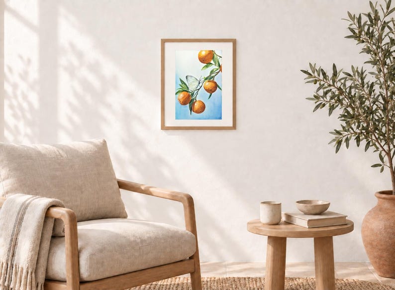 K&ouml;nnte beinhalten: Ein gerahmter Wandkunstdruck mit einer Aquarellillustration eines Zweigs mit vier leuchtend orangefarbenen Zitrusfr&uuml;chten und gr&uuml;nen Bl&auml;ttern vor einem sanft blauen Hintergrund, mit einem kleinen wei&szlig;en Schmetterling auf dem Zweig.