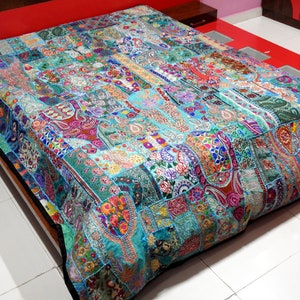 May include: A colourful patchwork quilt with a turquoise background. The quilt is made of various fabrics and features intricate embroidery and sequins.