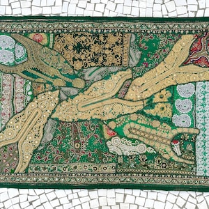May include: A rectangular green textile with intricate embroidery and patchwork. The design features gold and cream-colored floral and paisley patterns, with a dark green border. The textile is likely a decorative wall hanging or tapestry.