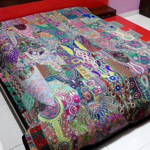 May include: A colourful patchwork quilt with intricate embroidery and sequins. The quilt is made of various fabrics in shades of green, blue, pink, and red. It features a variety of floral and geometric patterns.