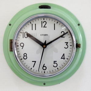 May include: A vintage green wall clock with a white face and black hands. The clock has a chrome bezel and the word "CITIZEN" printed on the face.