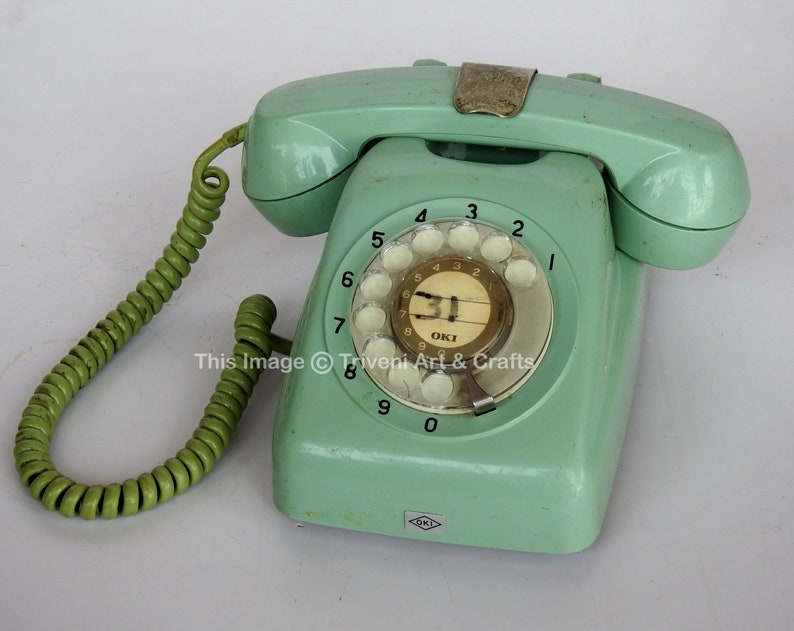 May include: A vintage green rotary dial phone with a green coiled cord. The phone has a white dial with black numbers and a small white label with the text "31" and "OKI".
