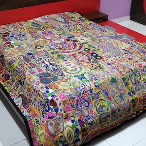 May include: A colourful patchwork quilt with intricate embroidery and sequins. The quilt is made of various fabrics in shades of yellow, blue, green, red, and pink. It features floral and paisley patterns.
