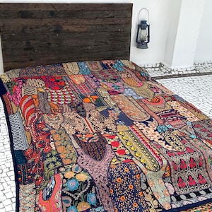 May include: A colourful patchwork quilt with a dark blue background. The quilt is made of various fabrics with different patterns and colours, including red, orange, yellow, green, blue, and purple. The quilt is laid out on a white tiled floor.