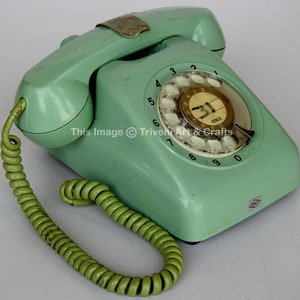 May include: A vintage green rotary dial phone with a white dial and a green coiled cord. The phone has the text "OKI" on the dial.